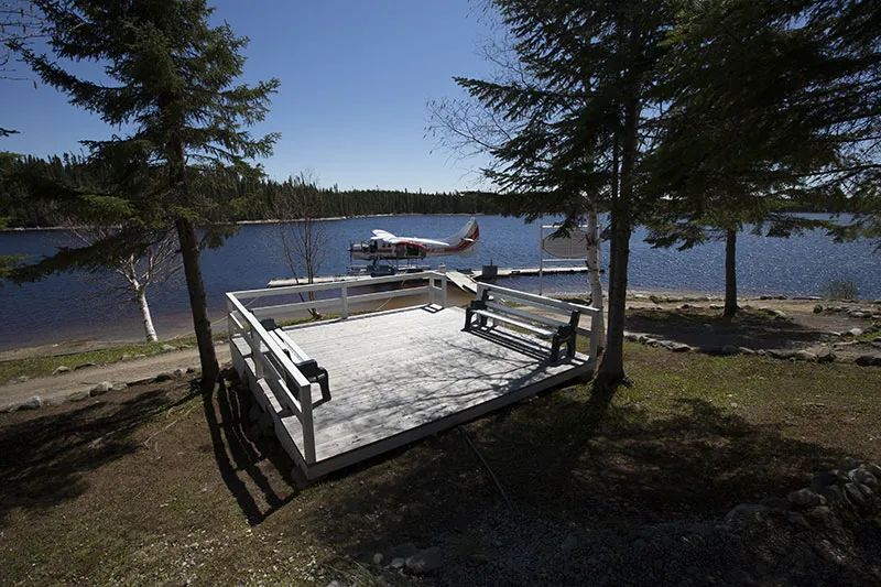Une plateforme avec bancs surplombe le lac et le quai où est stationné l'hydravion.