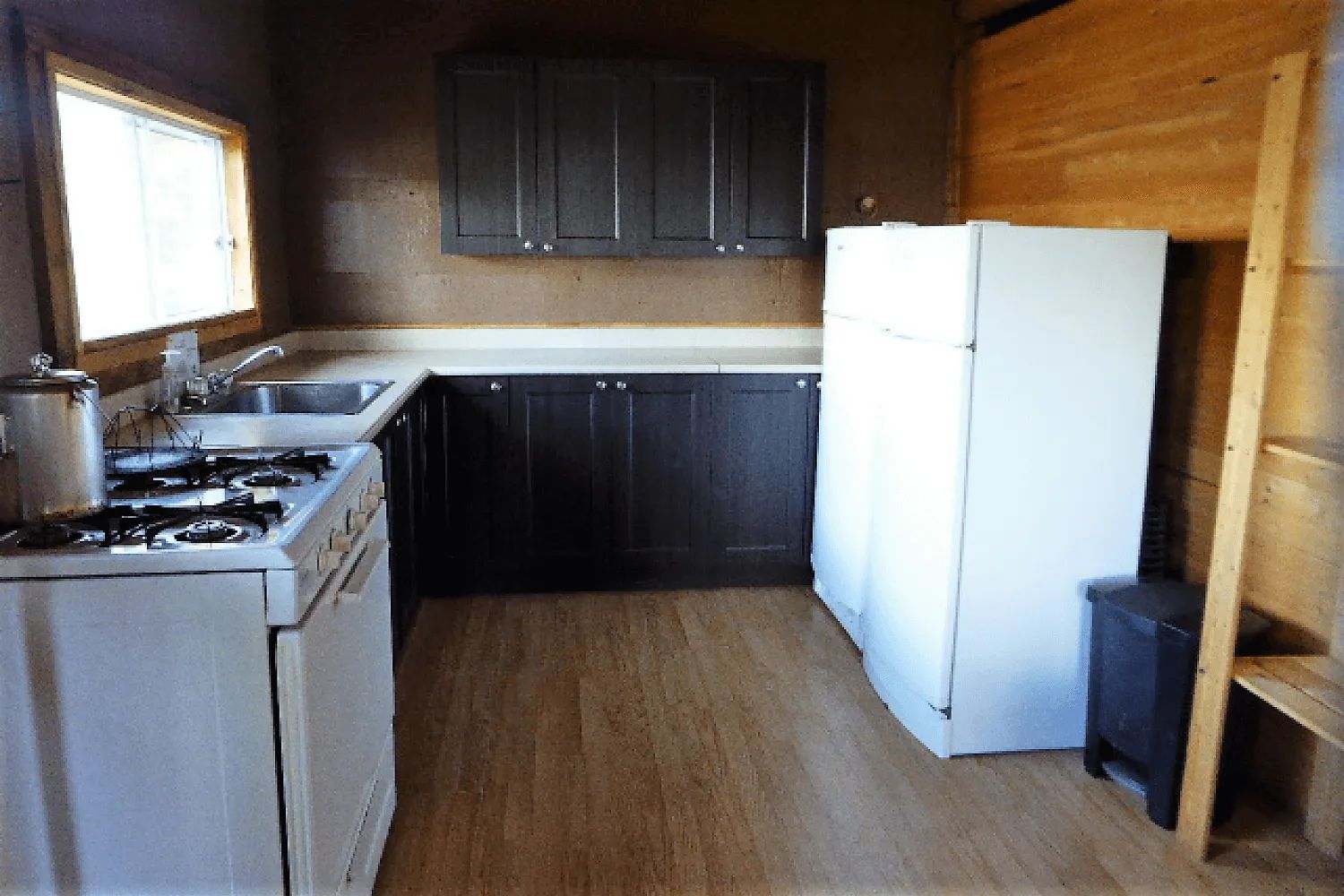 La cuisine fonctionnelle du chalet comprend une cuisinière, un évier et un grand réfrigérateur.