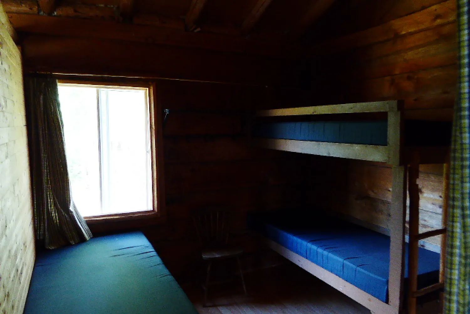 Cette chambre rustique comprend un lit superposé et un lit simple sous la fenêtre.