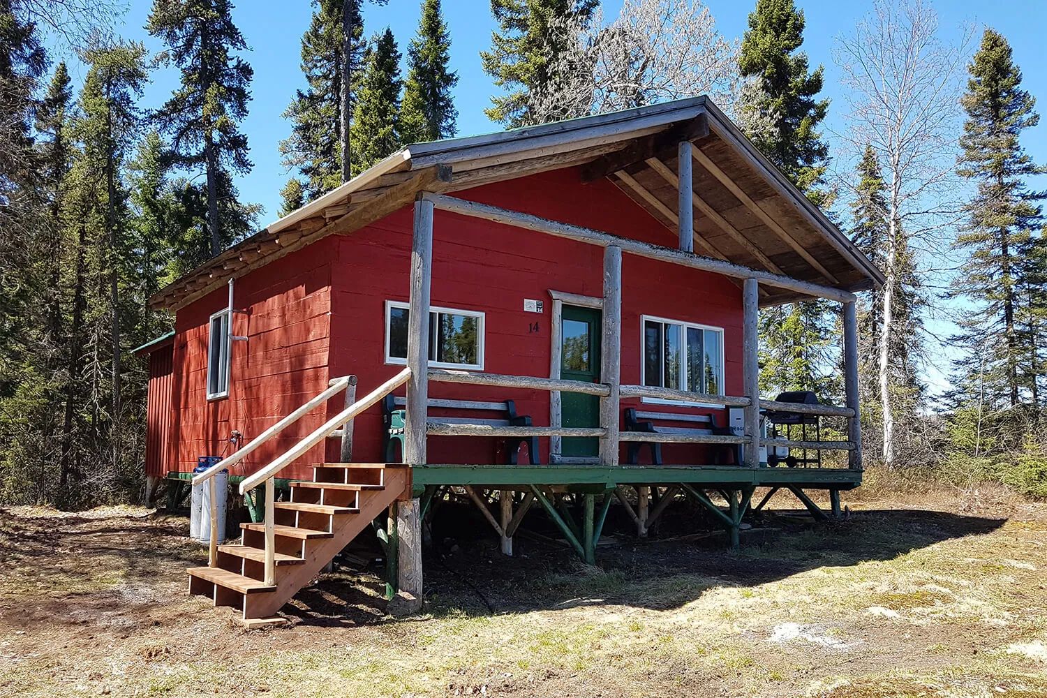 Le chalet numéro 14 dispose d'une galerie extérieure en bois située en forêt.