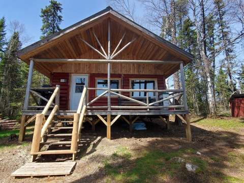 Front view of cabin 15 with its wooden porch surrounded by the forest.