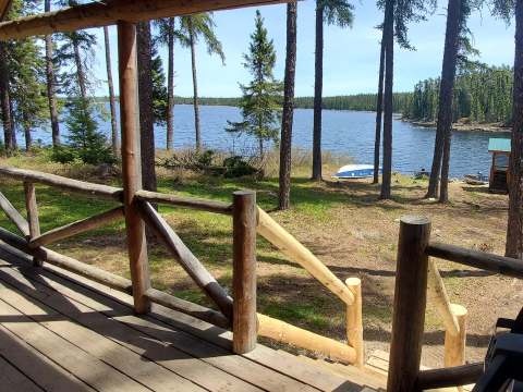 View of the lake and shoreline from the wooden porch of the cabin.