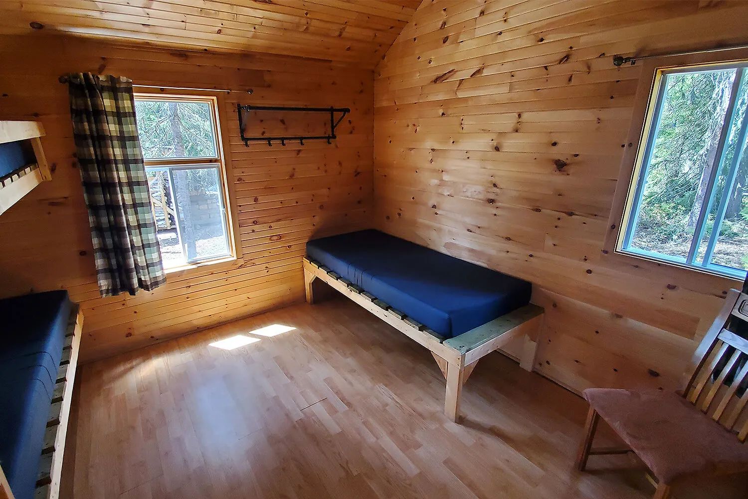 Interior view of the cabin bedroom featuring single beds and wood paneling walls.