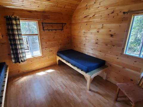 Interior view of the cabin bedroom featuring single beds and wood paneling walls.
