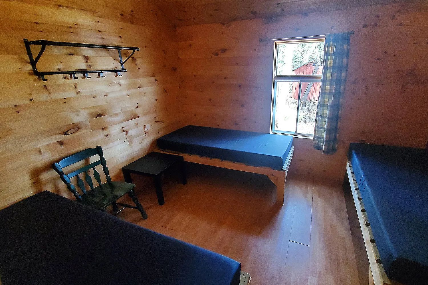 This rustic cabin bedroom features three single beds and wall-mounted storage.