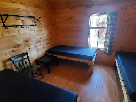 This rustic cabin bedroom features three single beds and wall-mounted storage.