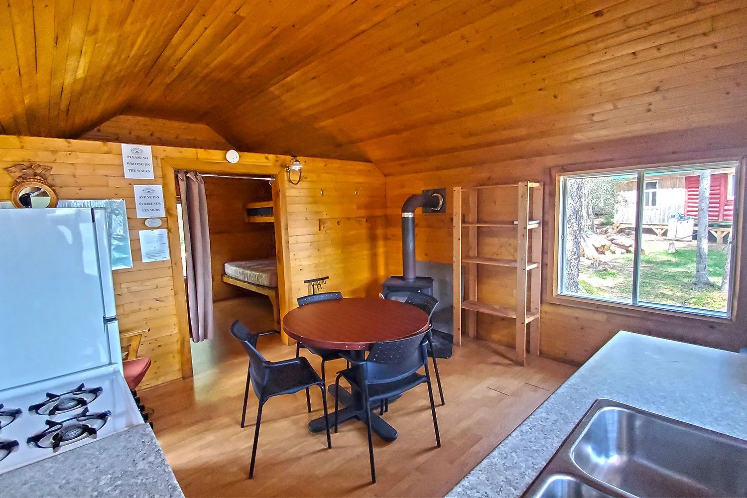 Vue de la cuisine et de la salle à manger ouverte avec poêle à bois dans le chalet 16.