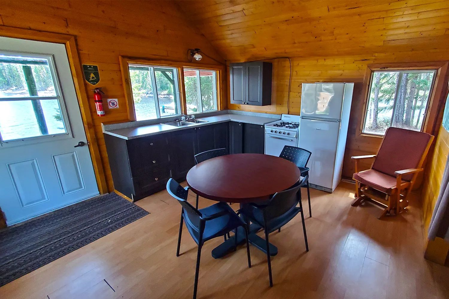 La cuisine fonctionnelle du chalet comprend une table à manger, un poêle et un réfrigérateur.