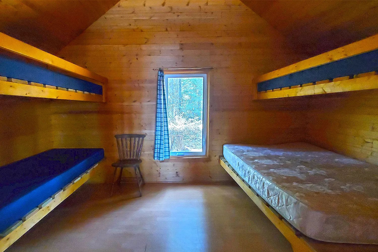 Cette chambre du chalet comprend deux lits superposés en bois et une fenêtre donnant sur la forêt.