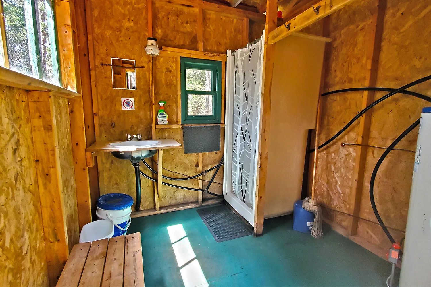 La salle de bain fonctionnelle du chalet est équipée d'une douche, d'un lavabo et d'un petit miroir.