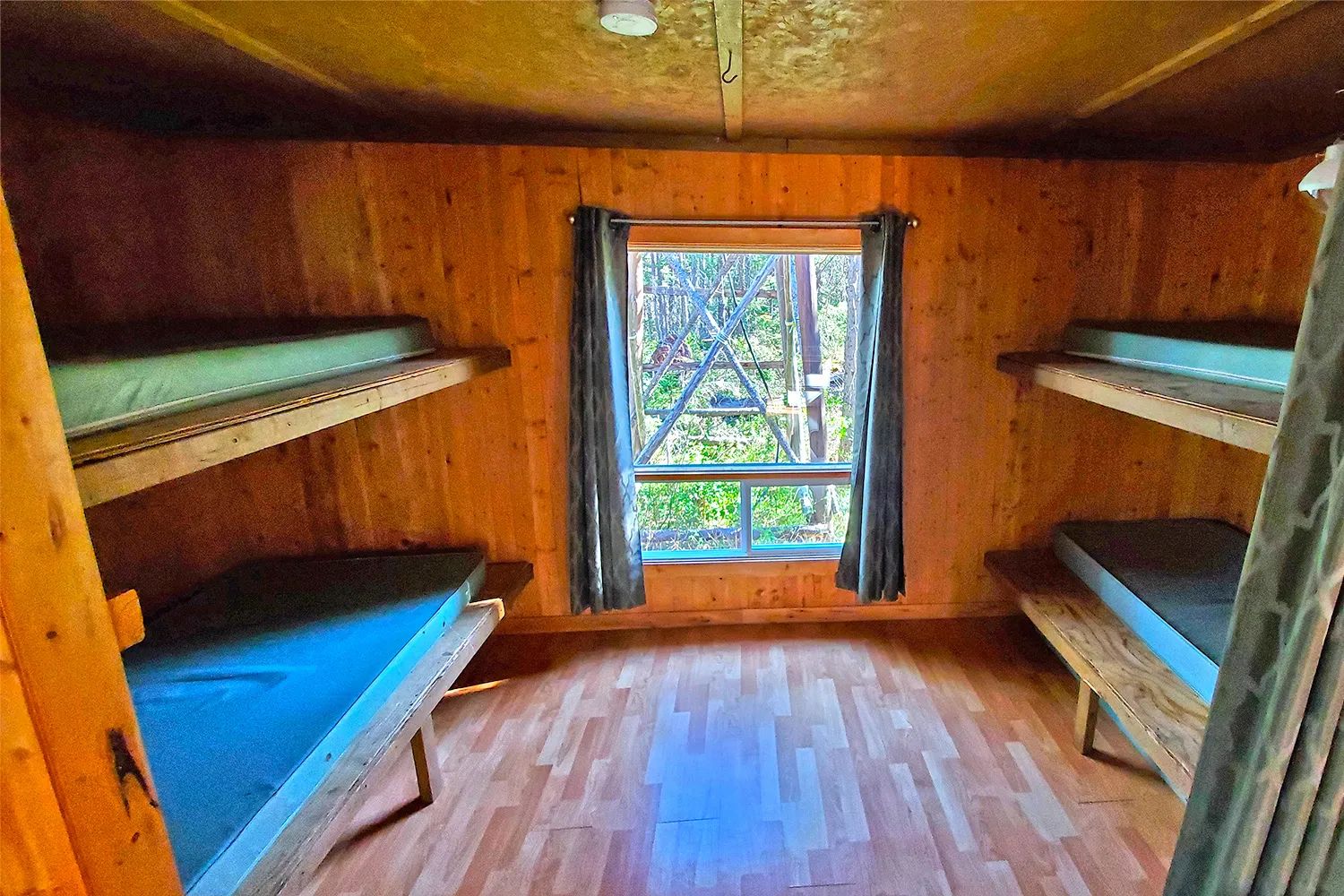 Cette chambre de chalet comprend deux lits superposés en bois et une fenêtre donnant sur la forêt.