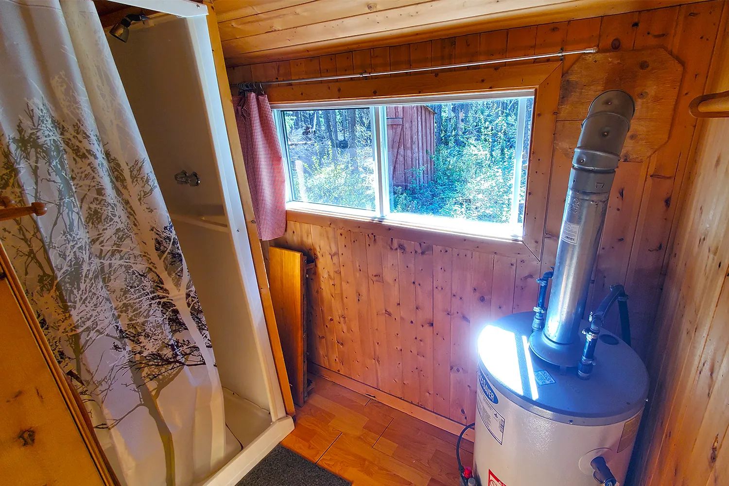 Vue intérieure d'une section du chalet incluant une douche et le chauffe-eau.