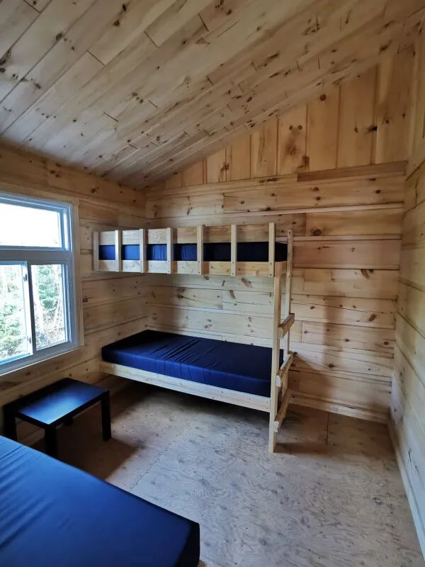Cette chambre de chalet comporte un lit superposé avec des murs en bois naturel.