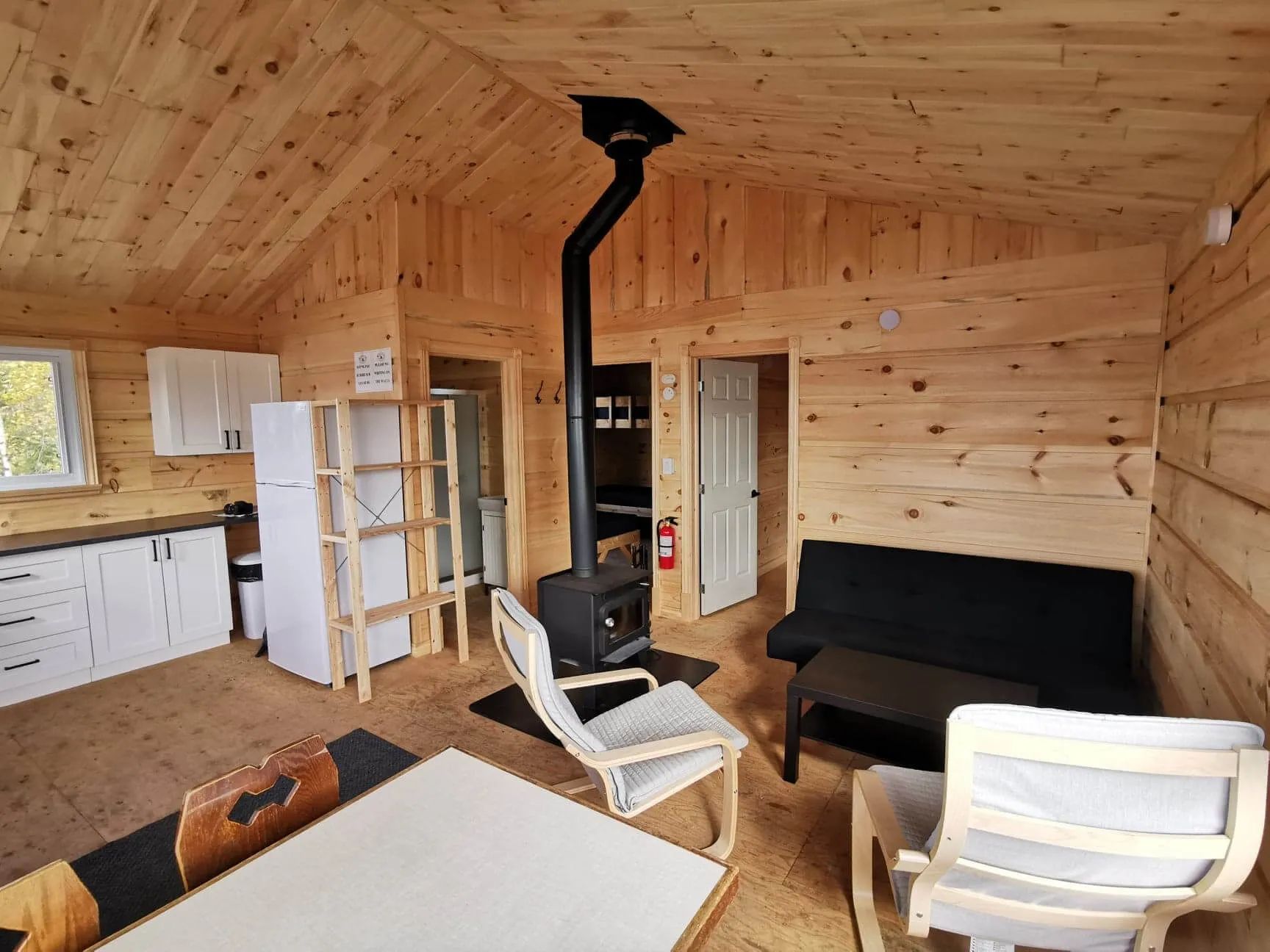 L'intérieur du chalet comprend une aire ouverte avec cuisine, salon, poêle à bois et salle à manger.