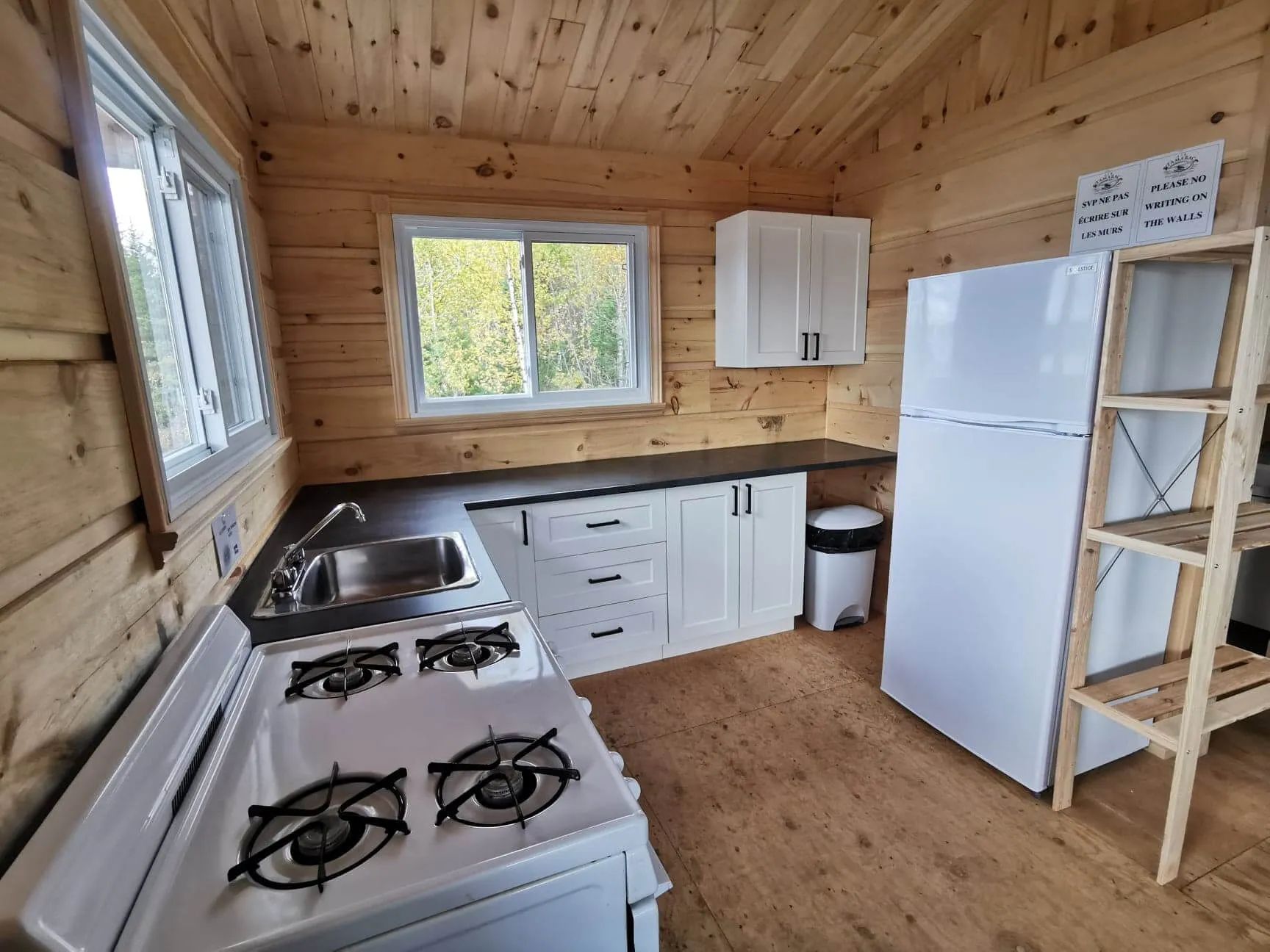 Cette cuisine lumineuse en bois comprend une cuisinière, un réfrigérateur et des armoires blanches.