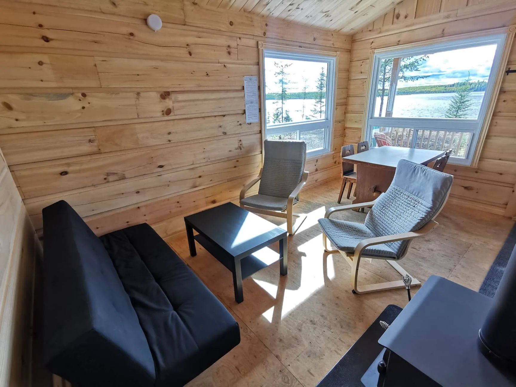Le salon du chalet comprend des fauteuils, un canapé-lit et une table avec vue sur le lac.