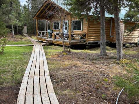 Vue du chalet numéro 21 avec son trottoir de bois menant à la galerie couverte.