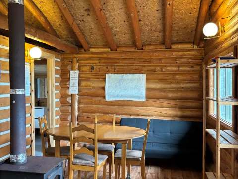 La salle à manger du chalet dispose d'une table, de chaises et d'un poêle à bois.