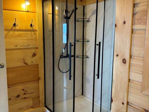 La salle de bain du chalet comprend une douche en coin moderne avec portes vitrées.