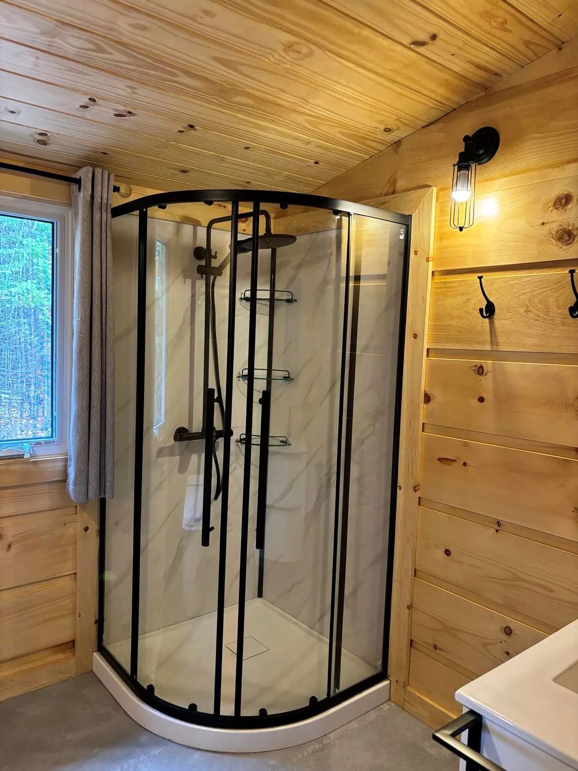 La salle de bain du chalet comporte une douche moderne avec une paroi vitrée et des murs en bois.