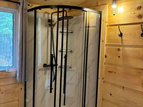 La salle de bain du chalet comporte une douche moderne avec une paroi vitrée et des murs en bois.