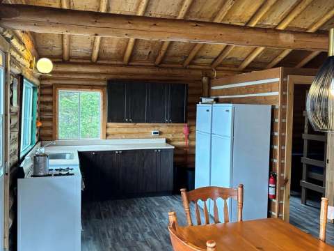 La cuisine équipée et la salle à manger ouverte du chalet en bois rond.