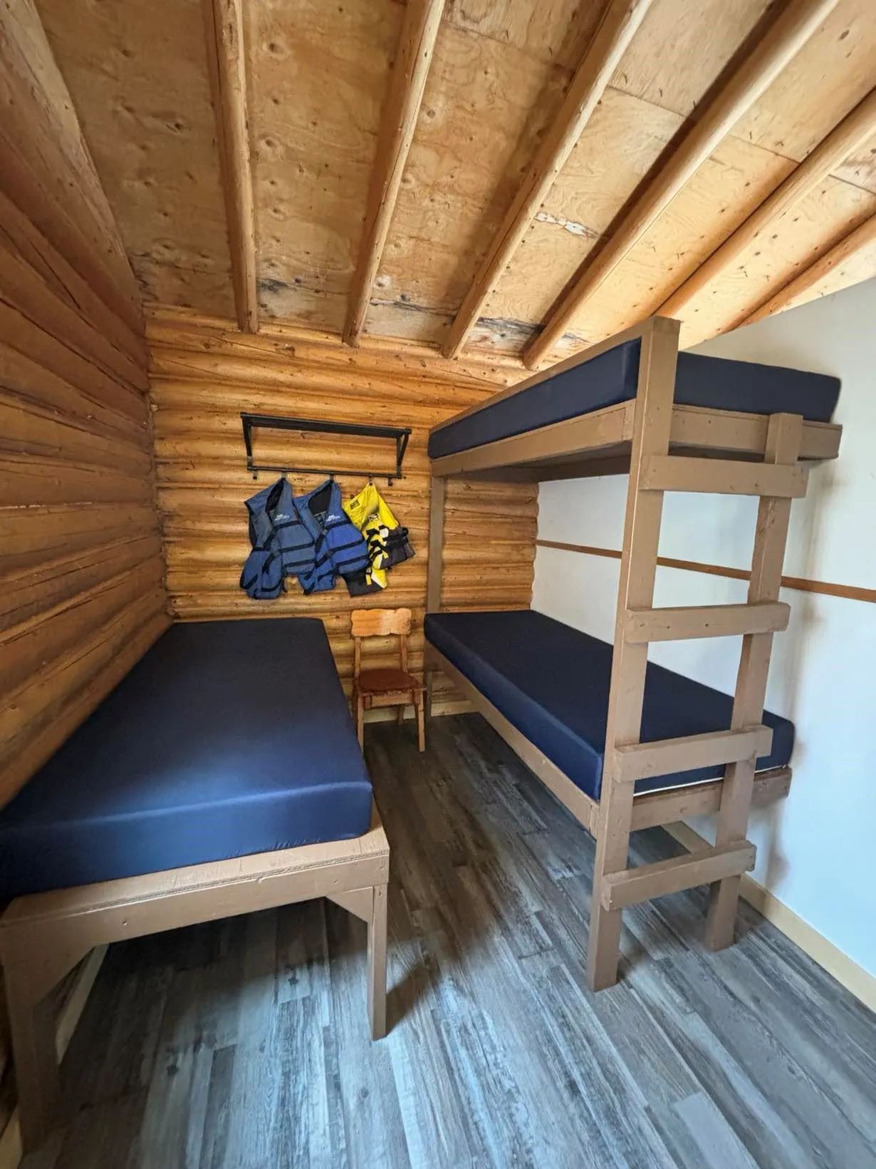 Cette chambre rustique comprend un lit simple et un lit superposé en bois.