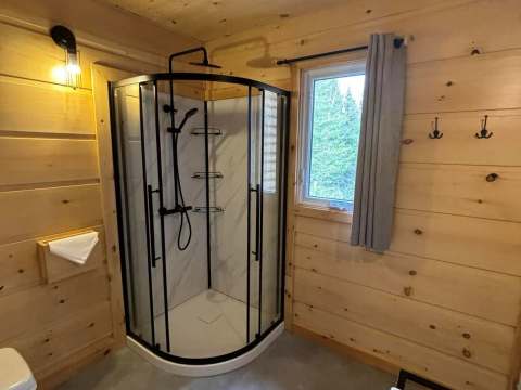 La salle de bain du chalet dispose d'une douche en coin avec une finition en bois naturel.