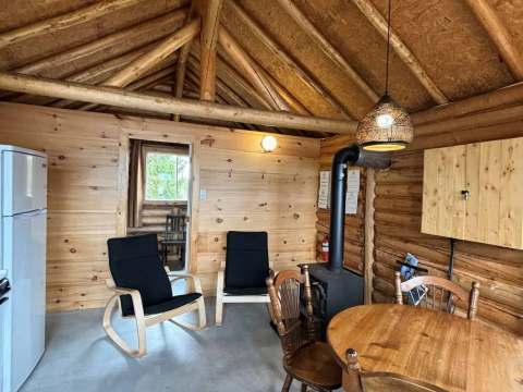 Espace de vie intérieur du chalet avec coin repas et poêle à bois.
