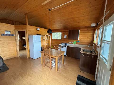 La cuisine fonctionnelle et l'espace repas du chalet sont aménagés avec des murs en lambris de bois.