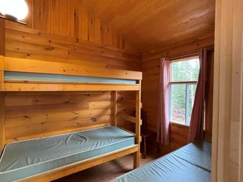 Cette chambre du chalet comprend un lit superposé et un lit simple avec une vue sur la forêt.