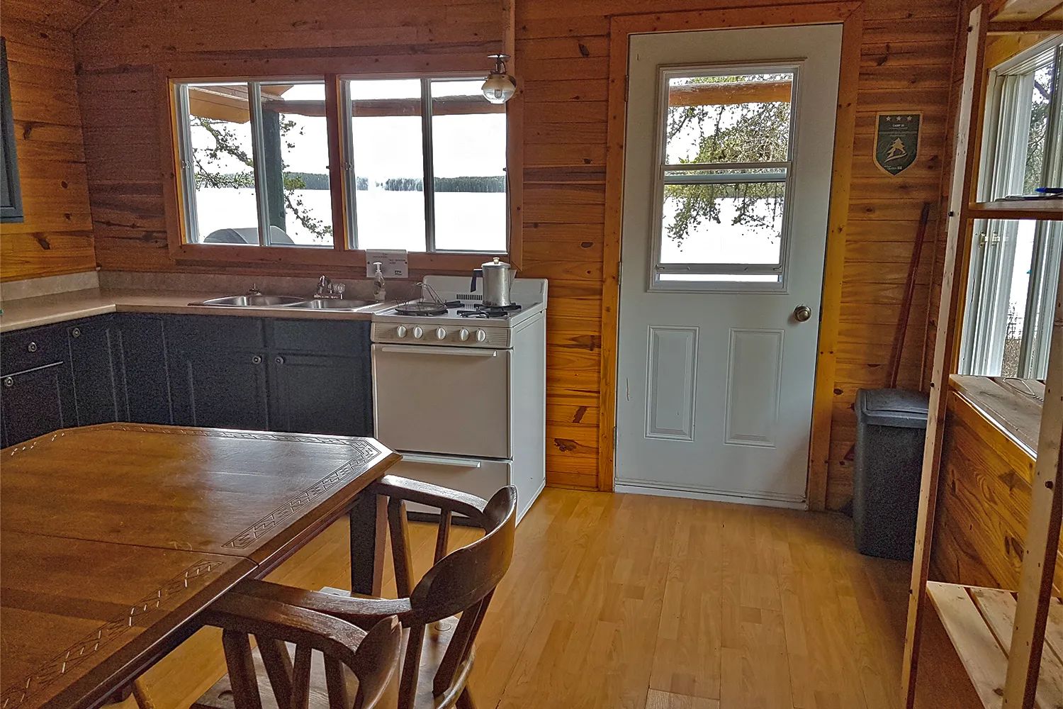 Vue de la cuisine et de la salle à manger du chalet avec vue sur l'extérieur.