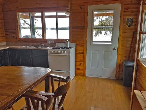 Vue de la cuisine et de la salle à manger du chalet avec vue sur l'extérieur.