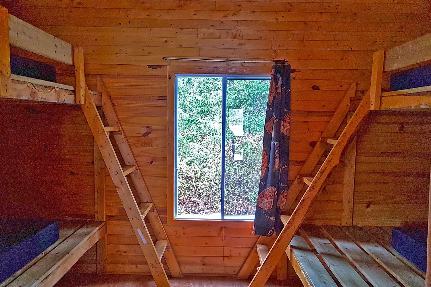 Cette chambre de chalet comprend deux lits superposés en bois avec vue sur la forêt.