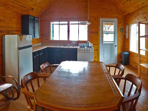 La cuisine et la salle à manger du chalet proposent un réfrigérateur, une cuisinière et une table.