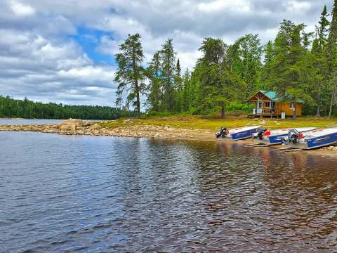 Le chalet est situé directement en bordure de l'eau avec des embarcations accostées devant.