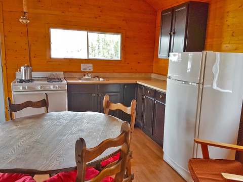 La cuisine équipée du chalet 31 comprend une table, une cuisinière et un réfrigérateur.