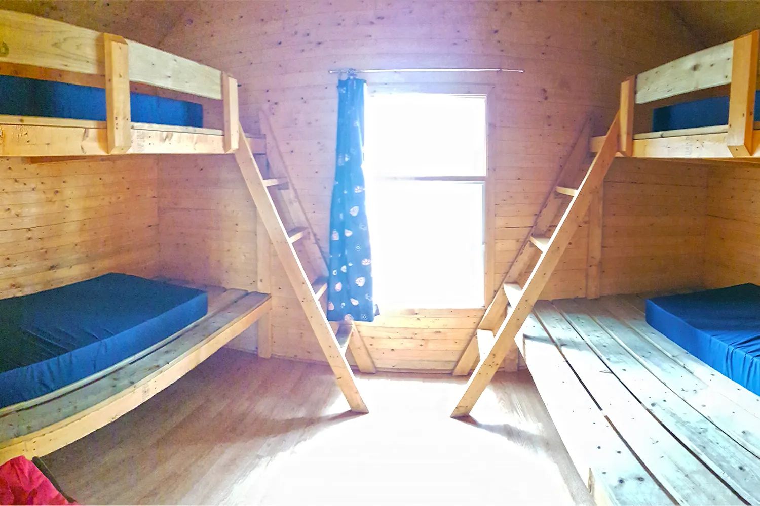 La chambre du chalet comprend deux lits superposés en bois avec des matelas bleus.