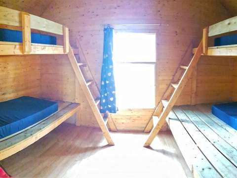 La chambre du chalet comprend deux lits superposés en bois avec des matelas bleus.