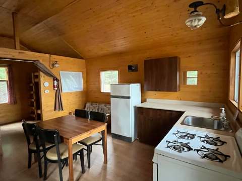 Vue de la cuisine et de la salle à manger du chalet avec ses murs en bois.