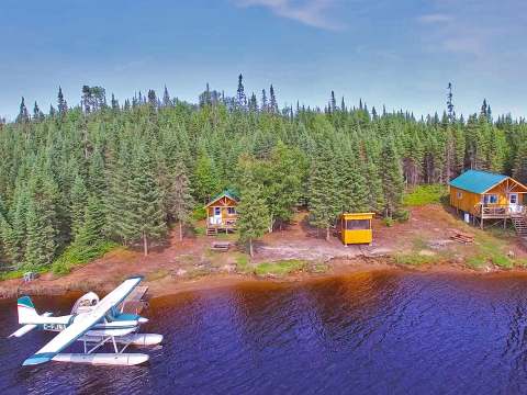 Vue aérienne des chalets situés en bordure de lac avec un hydravion accosté au quai.