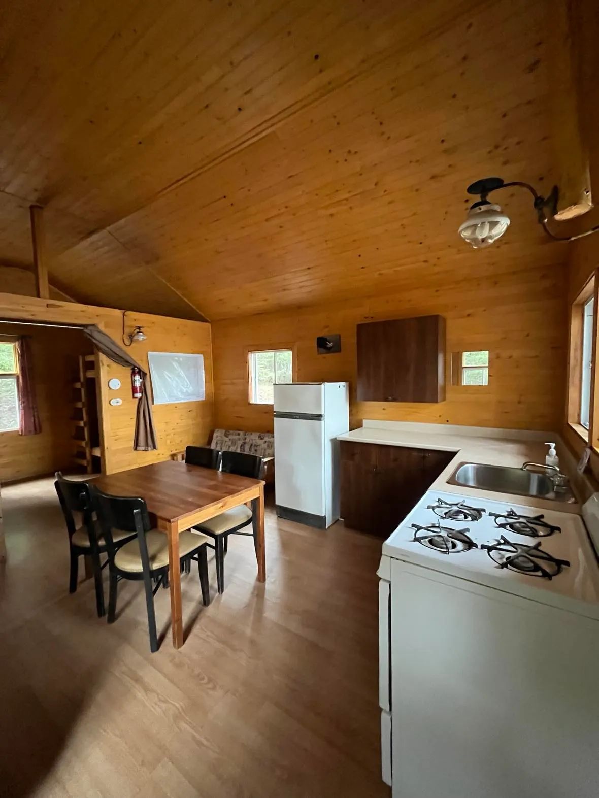 Vue de la cuisine et de la salle à manger du chalet avec ses murs en bois.