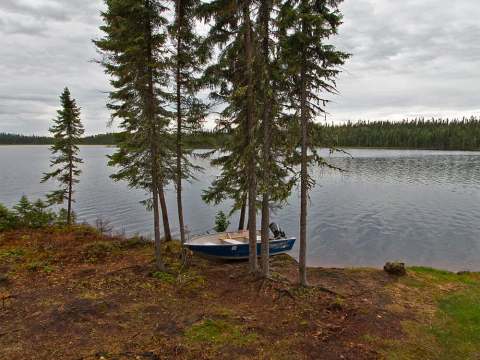 Vue sur le lac et l'embarcation depuis les marches de la galerie du chalet.