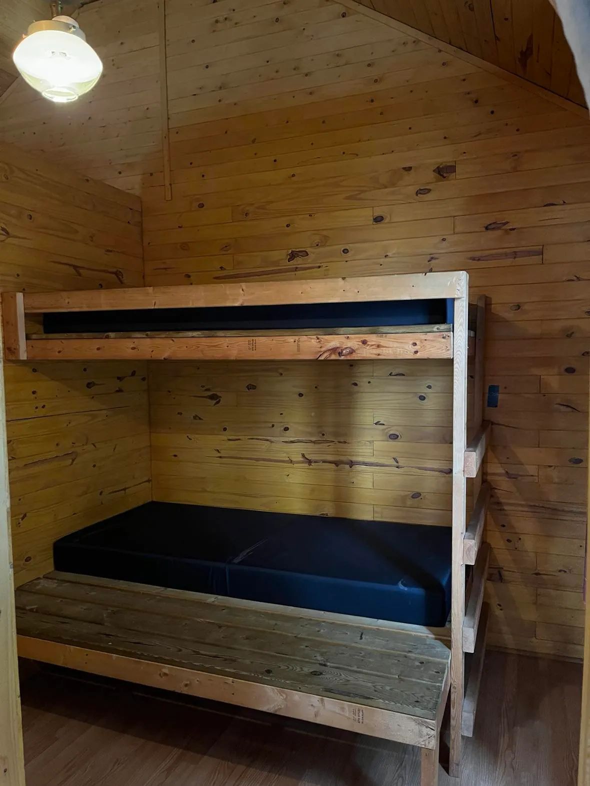 Un lit superposé en bois est aménagé à l'intérieur du chalet.