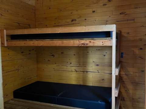 Un lit superposé en bois est aménagé à l'intérieur du chalet.