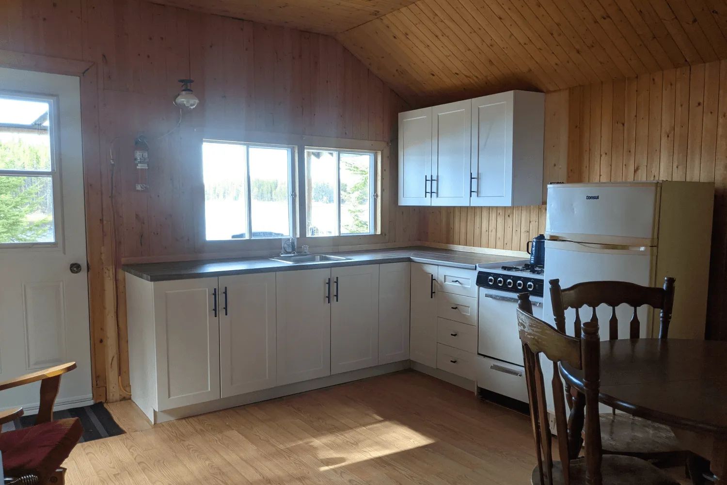 Cette cuisine équipée en bois comprend un réfrigérateur, une cuisinière et un coin repas.