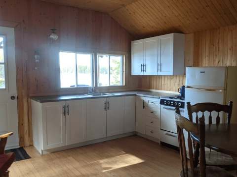 Cette cuisine équipée en bois comprend un réfrigérateur, une cuisinière et un coin repas.