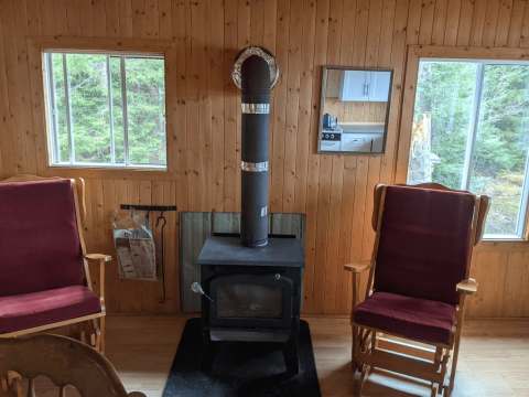 Le salon du chalet est équipé d'un poêle à bois et de deux chaises berçantes face aux fenêtres.