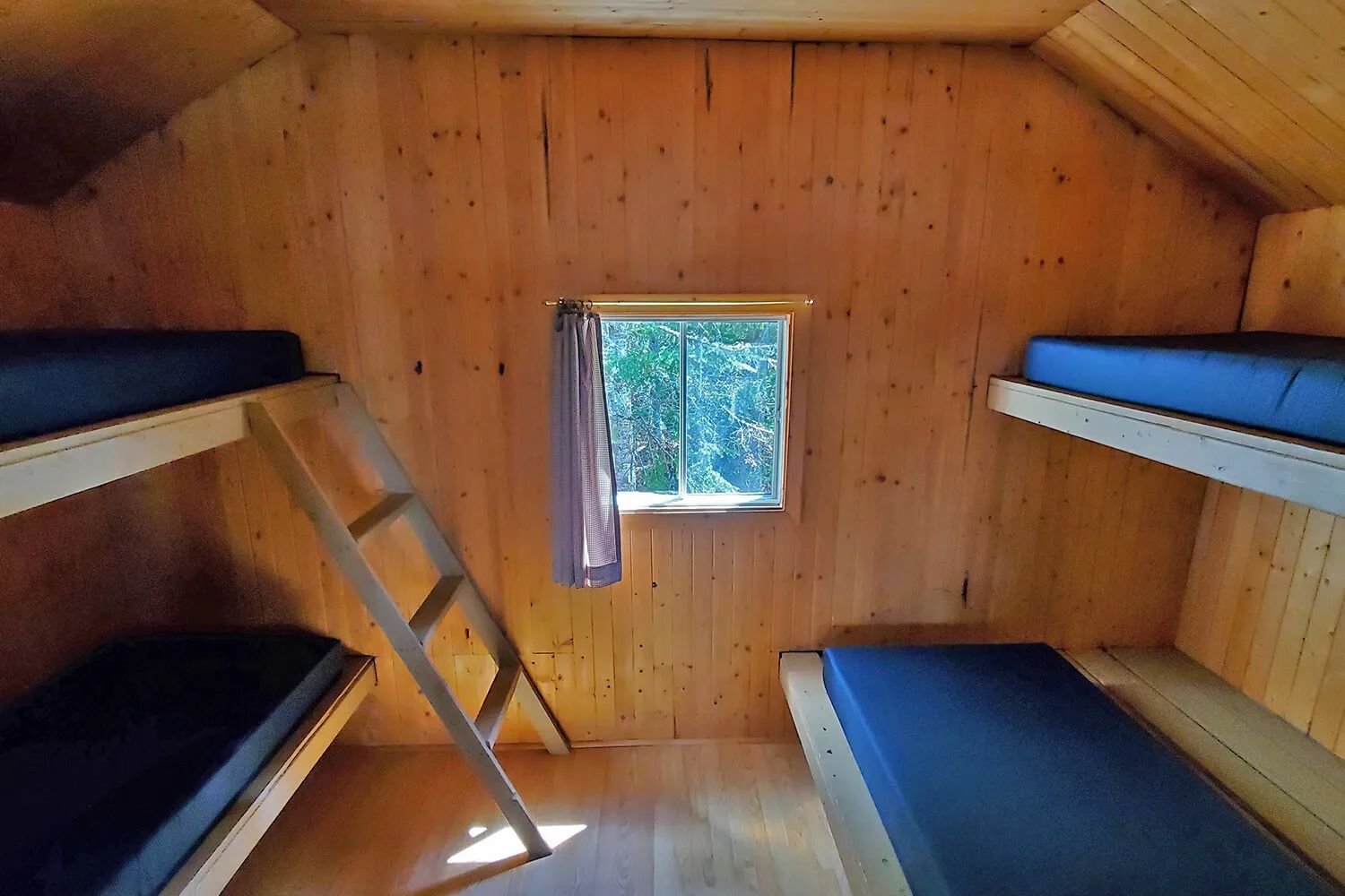 Cette chambre comporte des lits superposés en bois dans une ambiance rustique.