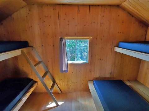 Cette chambre comporte des lits superposés en bois dans une ambiance rustique.